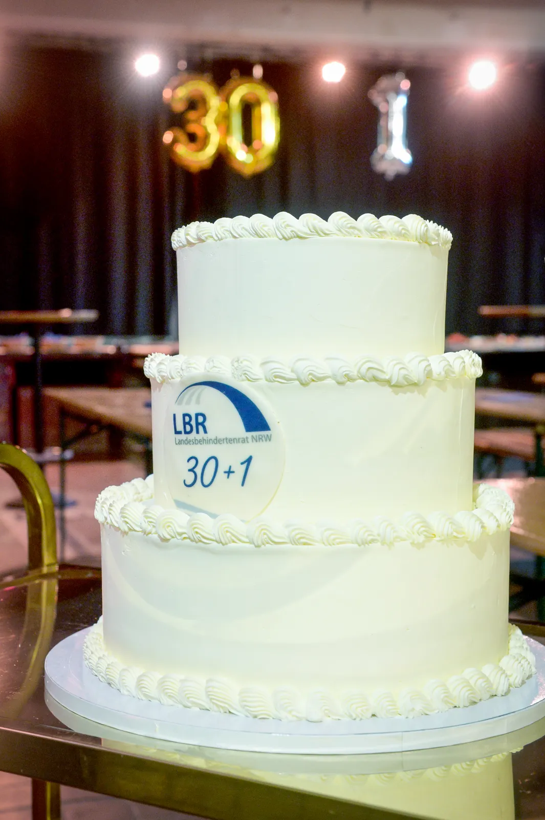 Dreistöckige weiße Jubiläumstorte mit LBR-Logo und goldenen Kerzen „30“ und „1“.